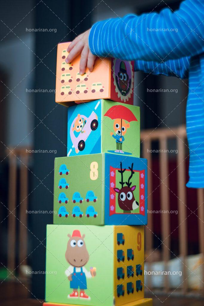 عکس با کیفیت کودک در حال چیدن مربع های کوچک