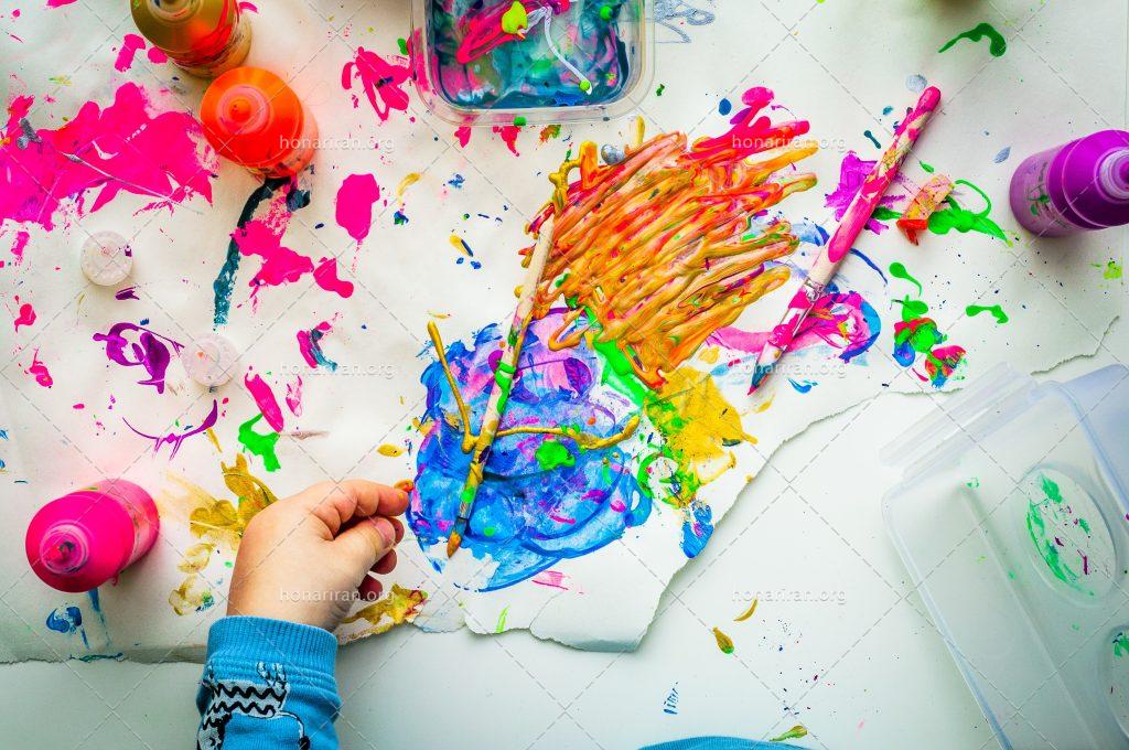 عکس با کیفیت کودک در حال بازی با رنگ ها