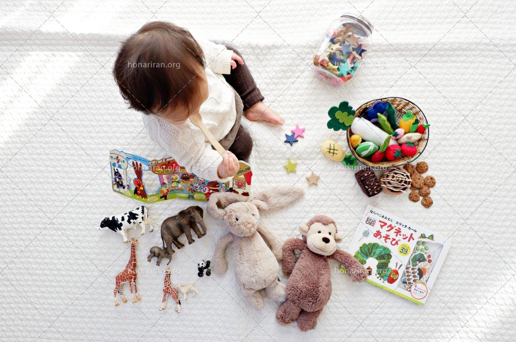 عکس با کیفیت اسباب بازی های ریخته شده در کنار کودک