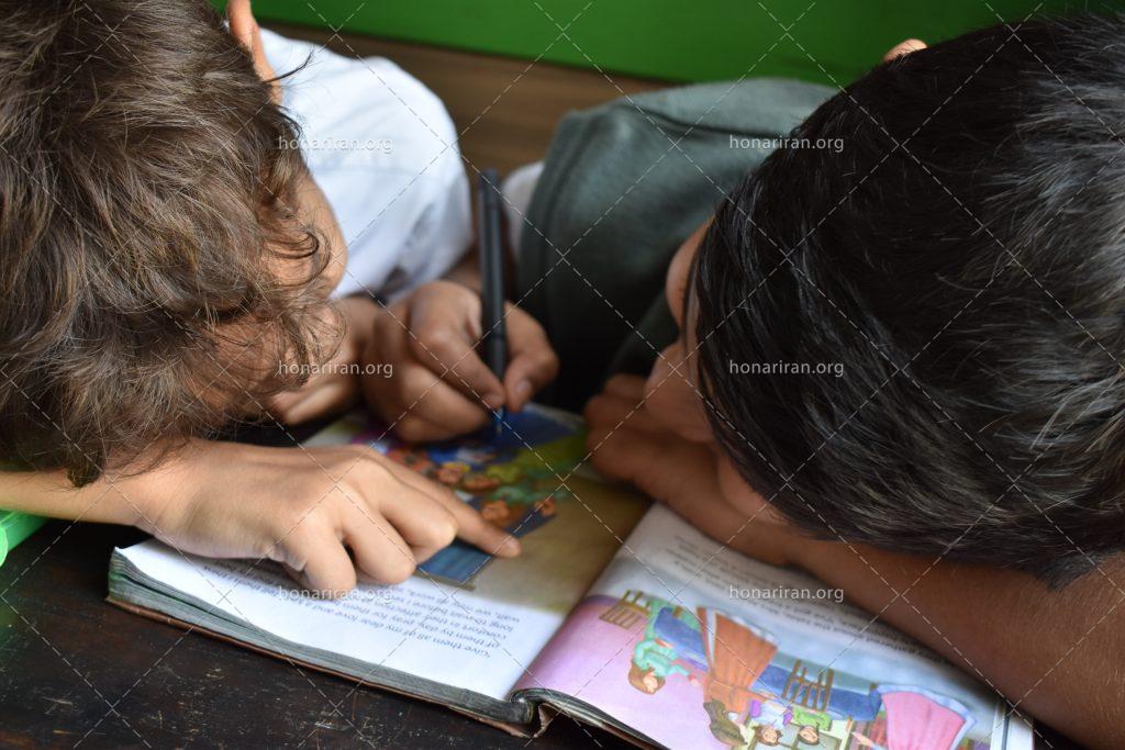 عکس با کیفیت دو پسر بچه در حال نوشتن مشق