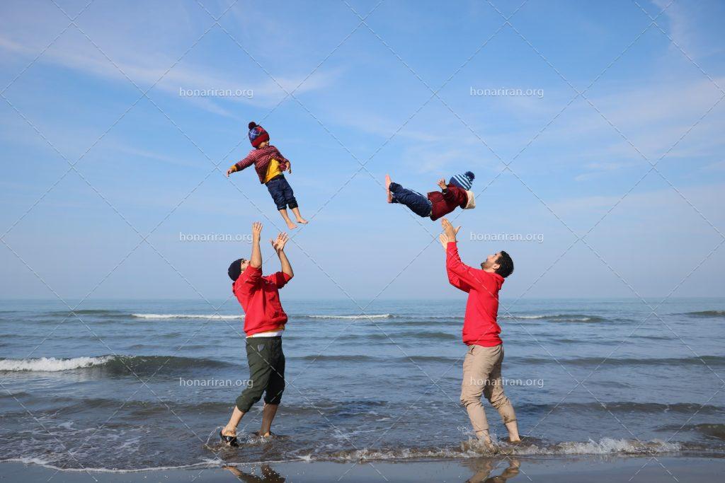 عکس با کیفیت دو پدر در حال بالا انداختن و بازی کردن با بچه های خود