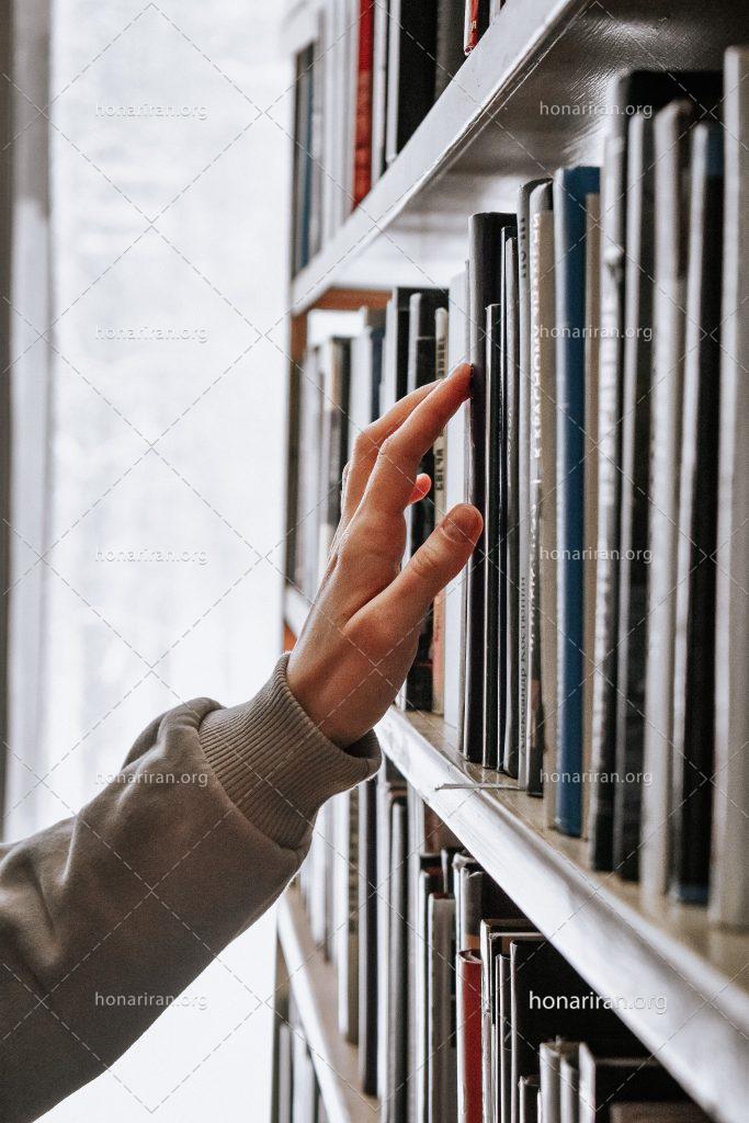 عکس با کیفیت مرد در حال جستوجو در بین کتاب ها
