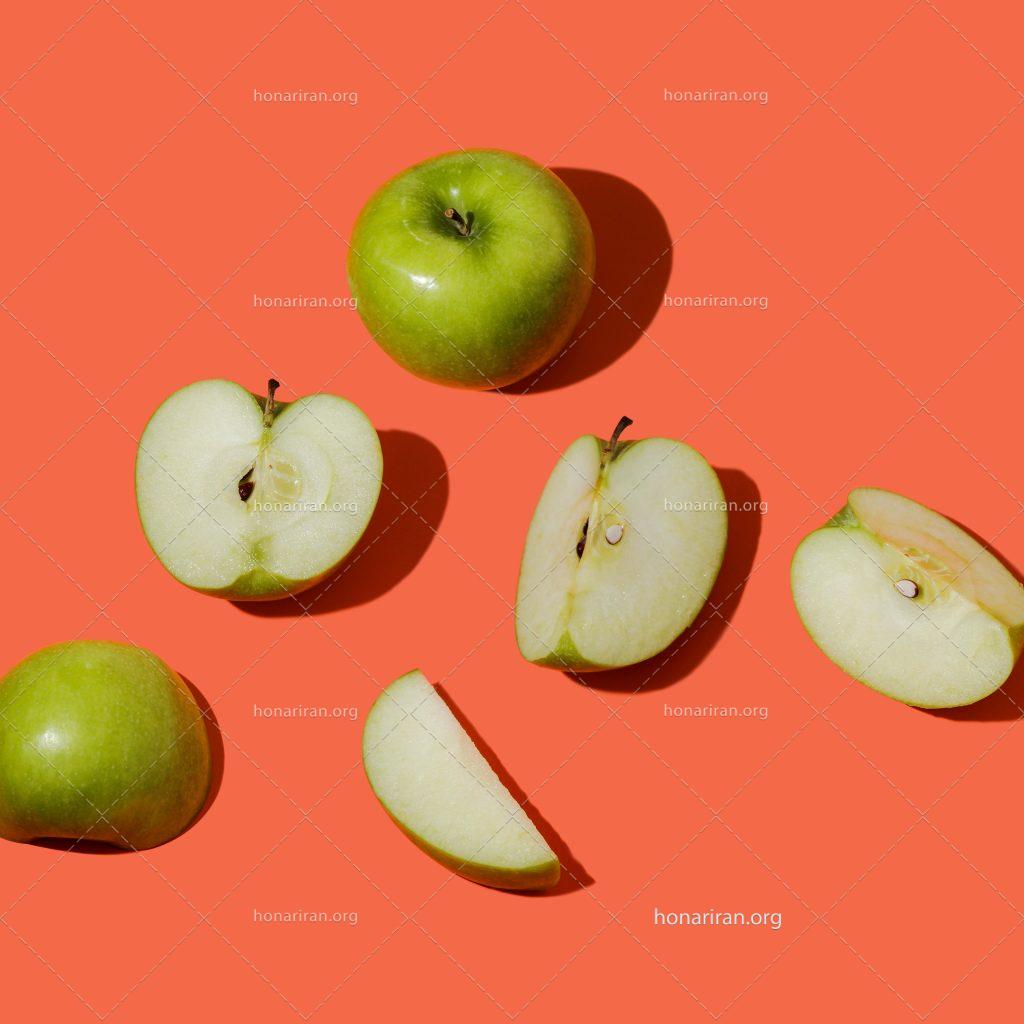 عکس با کیفیت دو سیب سبز در کنار برش های سیب