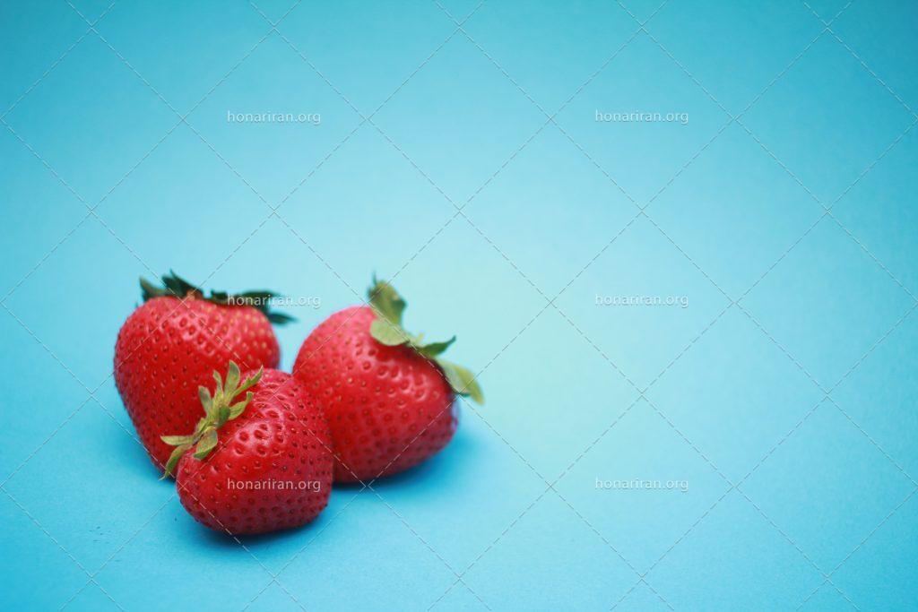 عکس با کیفیت سه توت فرنگی خوشمزه در بکگراند آبی