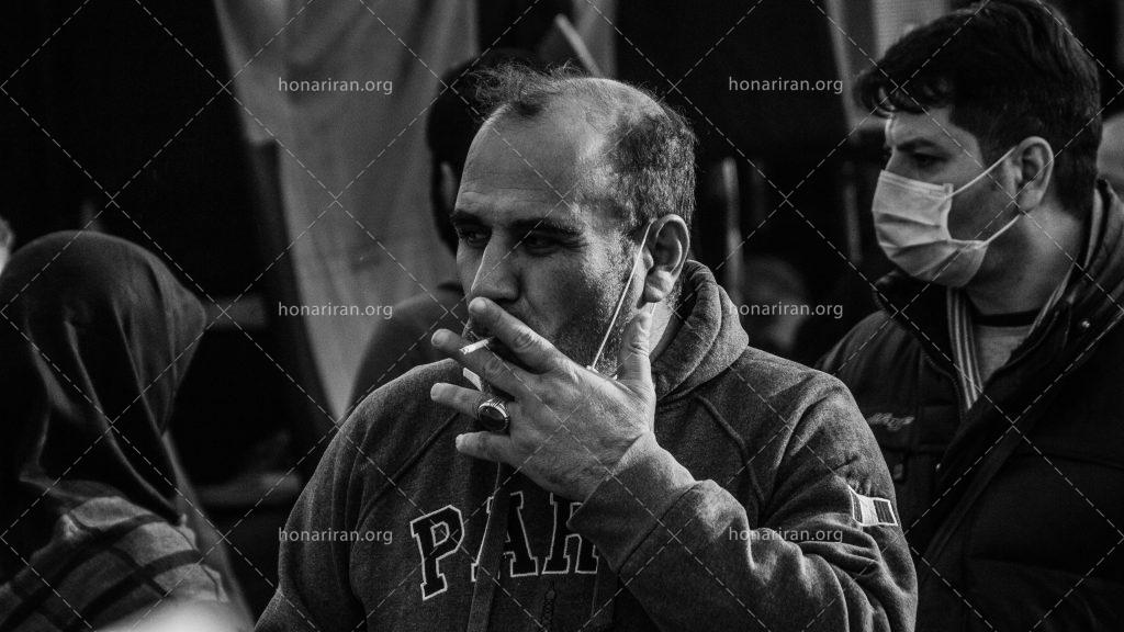 عکس با کیفیت مرد با هودی در حال کشیدن سیگار