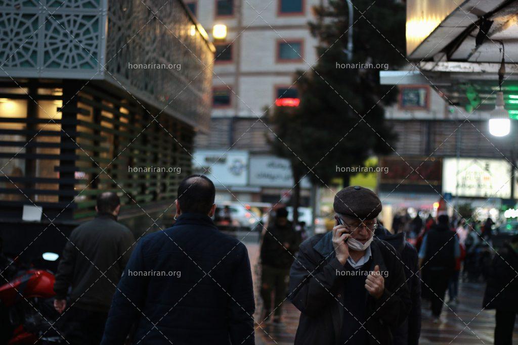 عکس با کیفیت خیابان بارانی و پیرمرد در حال صحبت با تلفن
