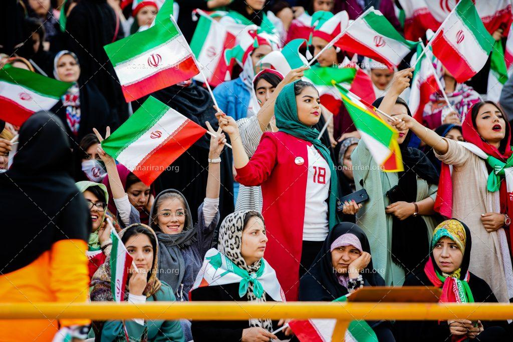 عکس با کیفیت زنان در استادیوم و پرچم در دستانشان