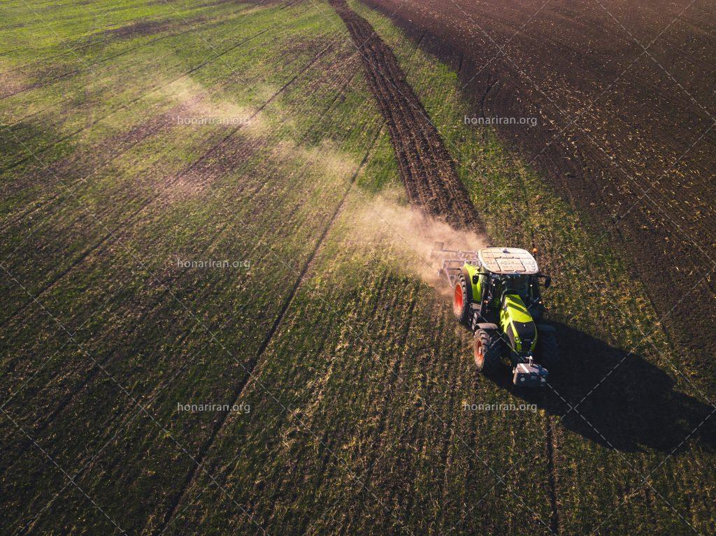 عکس با کیفیت تراکتور در حال شخم زدن زمین کشاورزی