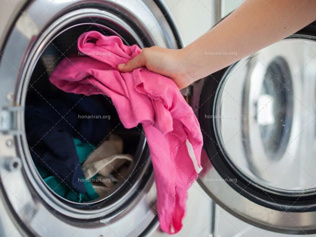 عکس با کیفیت زن در حال انداختن لباس در لباسشویی
