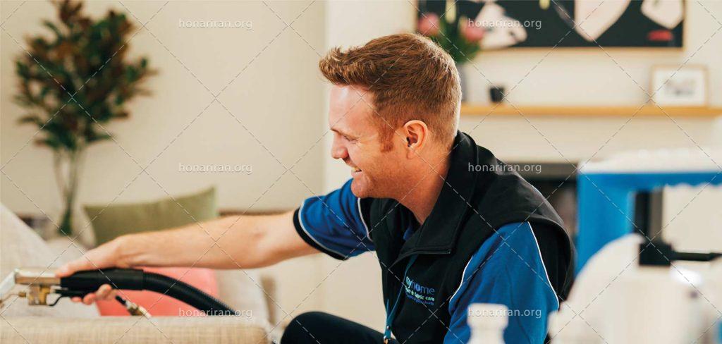 عکس با کیفیت مرد خندان در حال تمیز کردن مبل