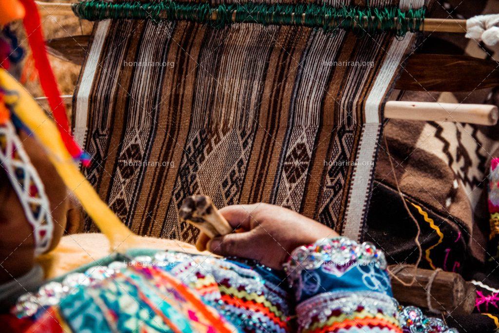 عکس با کیفیت زن با لباس محلی در حال بافتن گلیم