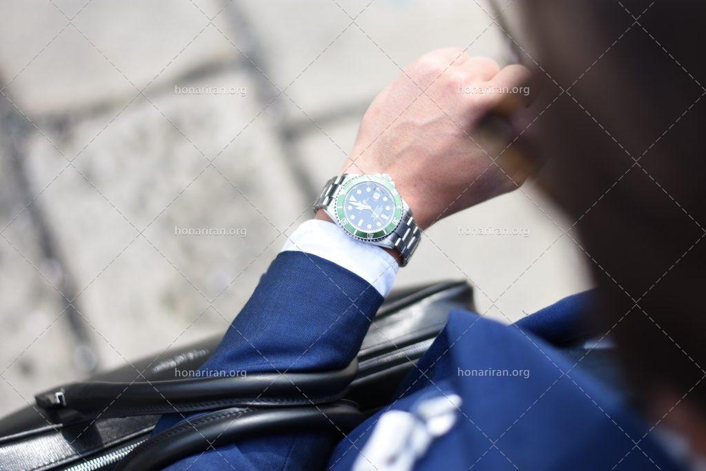 عکس با کیفیت مرد با کت آبی در حال نگاه کردن به ساعت مچی