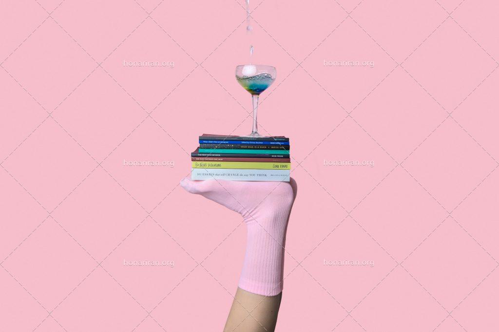 عکس با کیفیت جام نوشیدنی بر روی کتاب ها