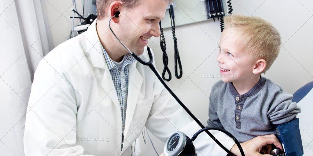 عکس با کیفیت پزشک با لبخند در کنار کودک