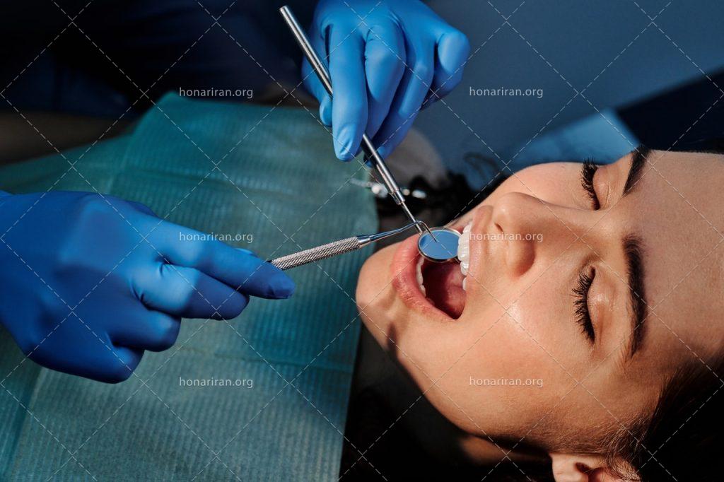 عکس با کیفیت دکتر در حال برسی دندان های زن